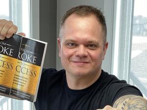 Derek Loepp with copies of the book he contributed to.