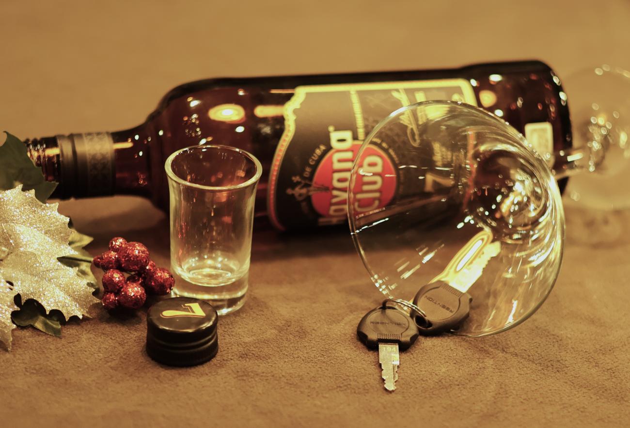 Car keys next to empty alcohol bottle.