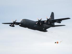A CC-130 Hercules dispatches a survival raft during training on 25 July, 2022 over Lake Winnipeg in Gimli, Manitoba.