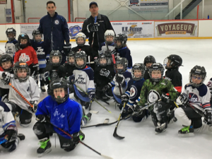 The Initiation Blue and White teams alongside Winnipeg Jets coaches Todd Woodcroft and Troy Stevens.