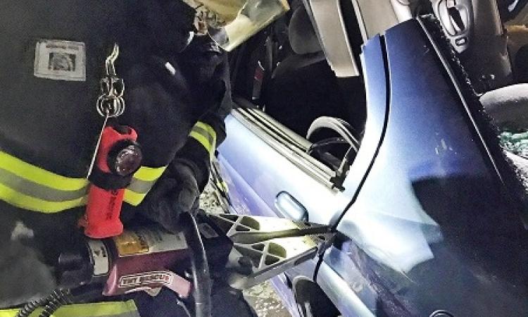 A Niverville firefighter using the jaws of life to open the dear door of a car.