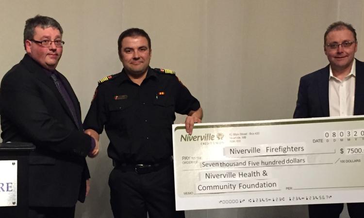 Andrew Neufeld and Ken Rempel of the Niverville Health and Community Foundation board present a donation to Fire Chief Keith Bueckert.