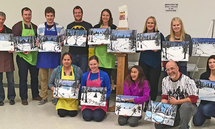 Paint night participants who off their art.