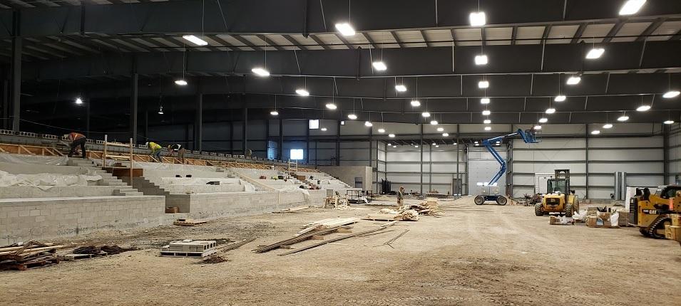 Photo 1: On the arena side of the building, seating has been installed. Concrete has yet to be poured over the ice surface.
