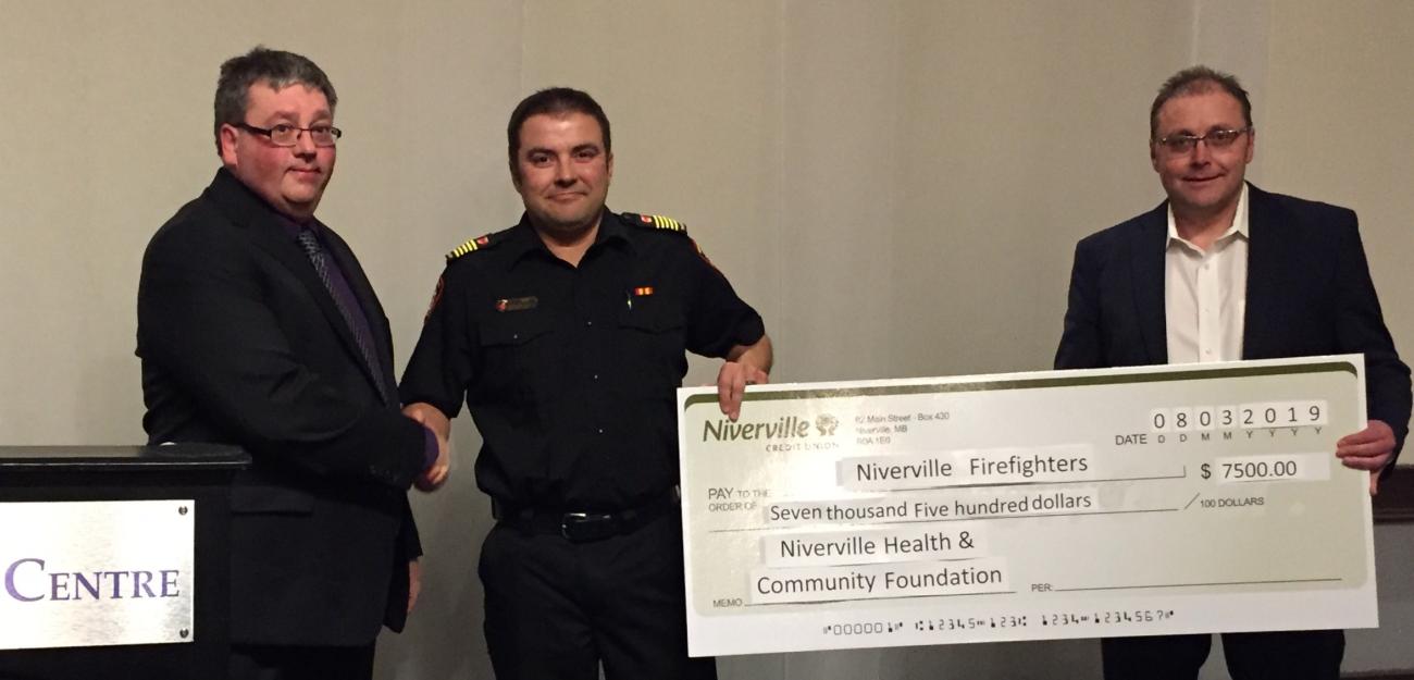 Andrew Neufeld and Ken Rempel of the Niverville Health and Community Foundation board present a donation to Fire Chief Keith Bueckert.