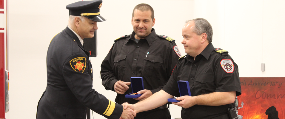 Fire Chief Scott Weir and Deputy Chief Paul Houle collect their service medals from Robert Pike, Manitoba’s Deputy Fire Commissioner.